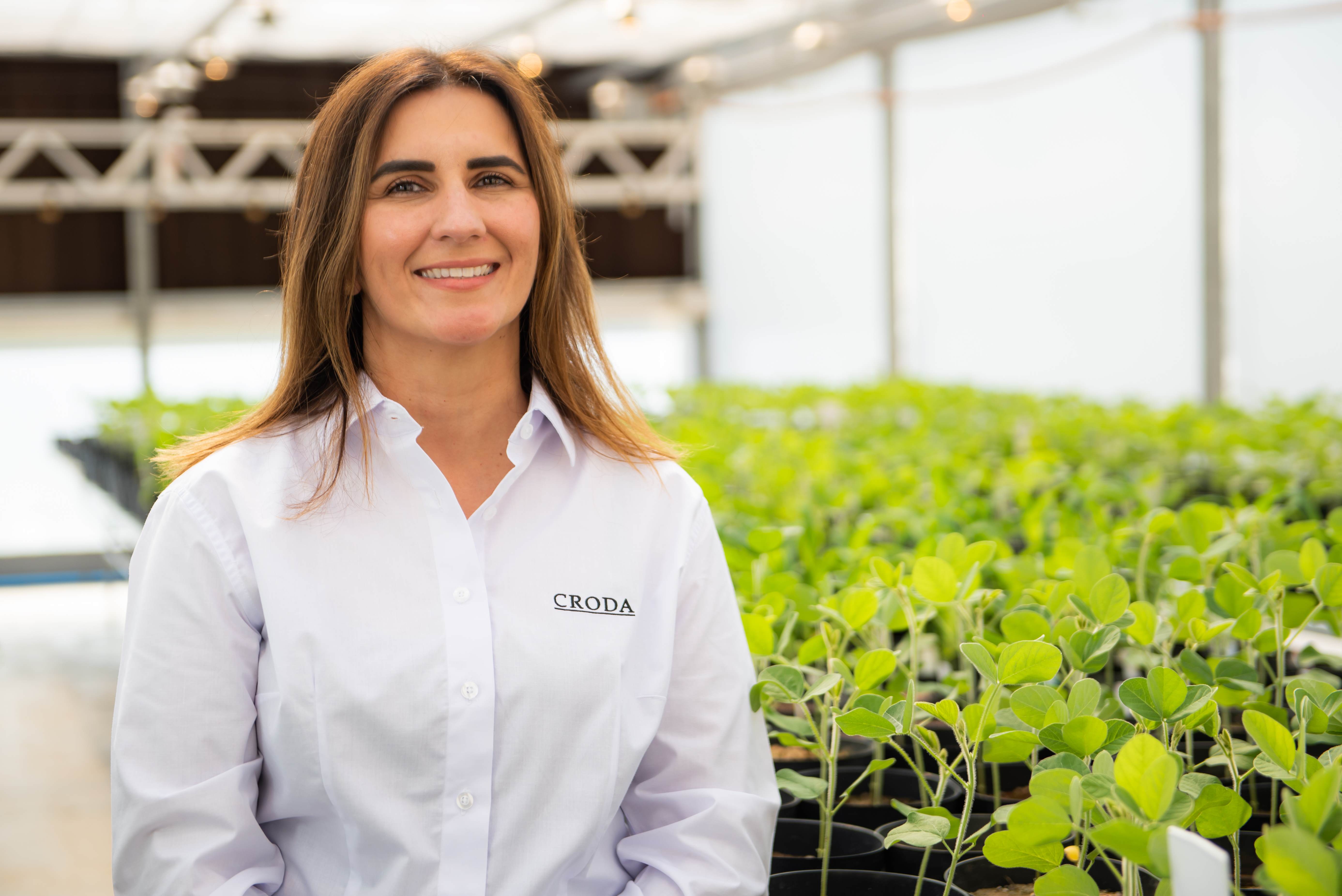 A Croda employee standing beside a field of crops in greenhouse